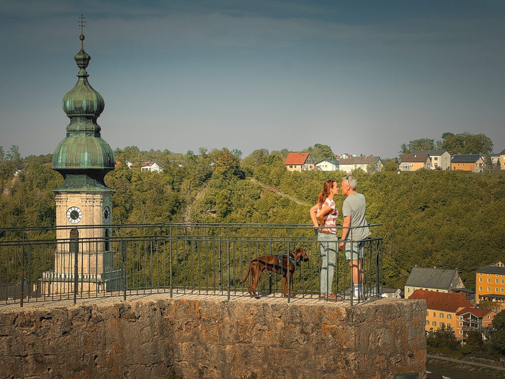 Couple with dog enjoying a romantic moment on a viewing platform at Burghausen Castle in Bavaria, Germany